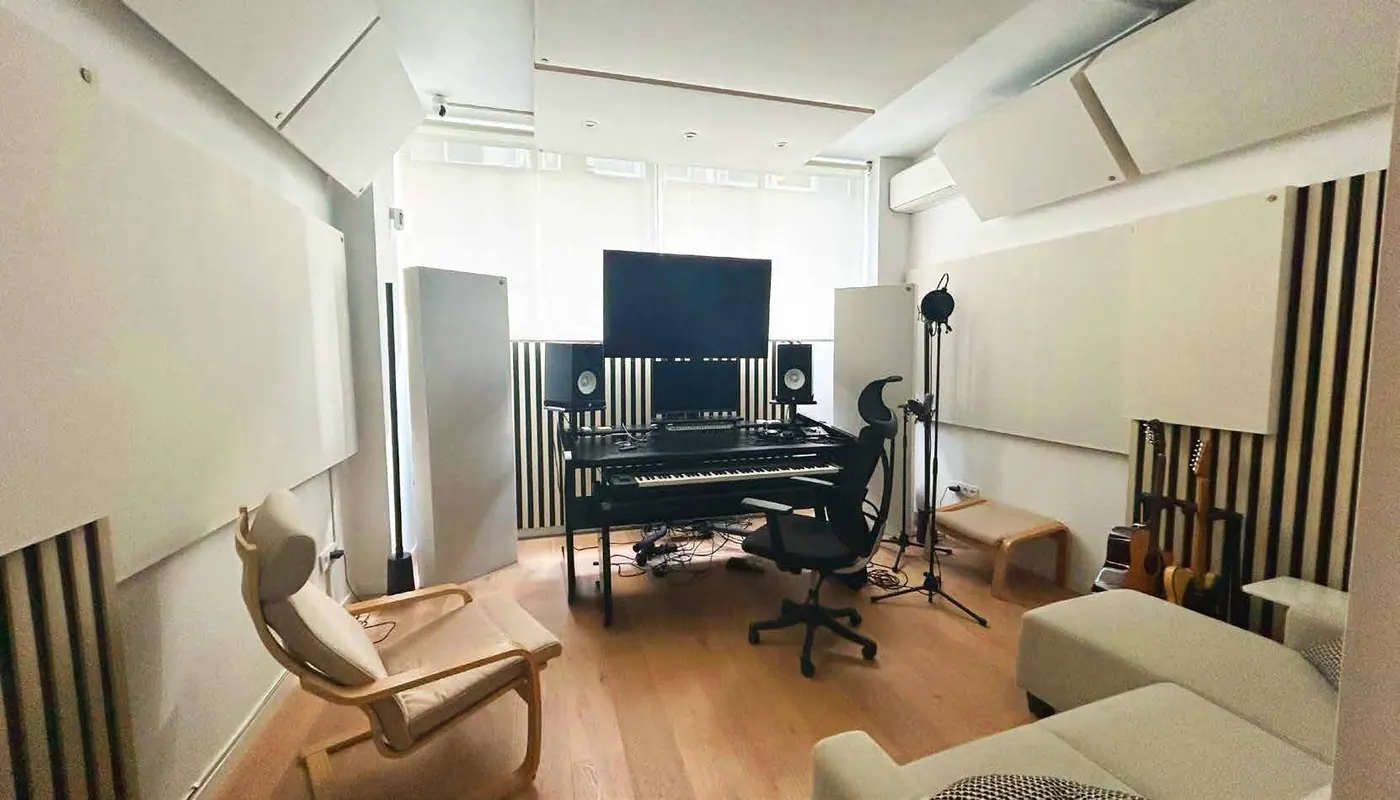 Vista lateral del estudio con sillón, mesa de producción y paneles acústicos